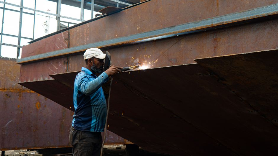 A welder skillfully works on a massive metal structure in an industrial setting. (Photo: Bornil Sarker / Pexels)