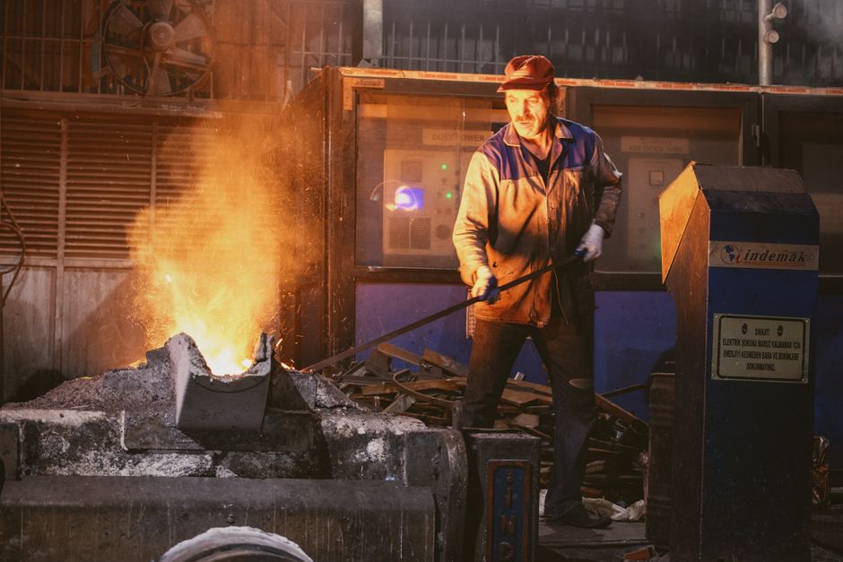 Photo of a worker overseeing molten metal in a factory setting, highlighting industrial labor. (Photo: Mehmet Turgut Kirkgoz / Pexels)