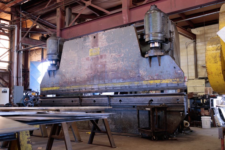 Massive metal press in a factory showcasing heavy machinery and industrial environment. (Photo: J E / Pexels)