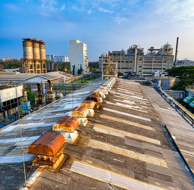 Exterior of aged shabby factory with rusty industrial buildings and mechanisms with pipes in town (Photo: Tom Fisk / Pexels)